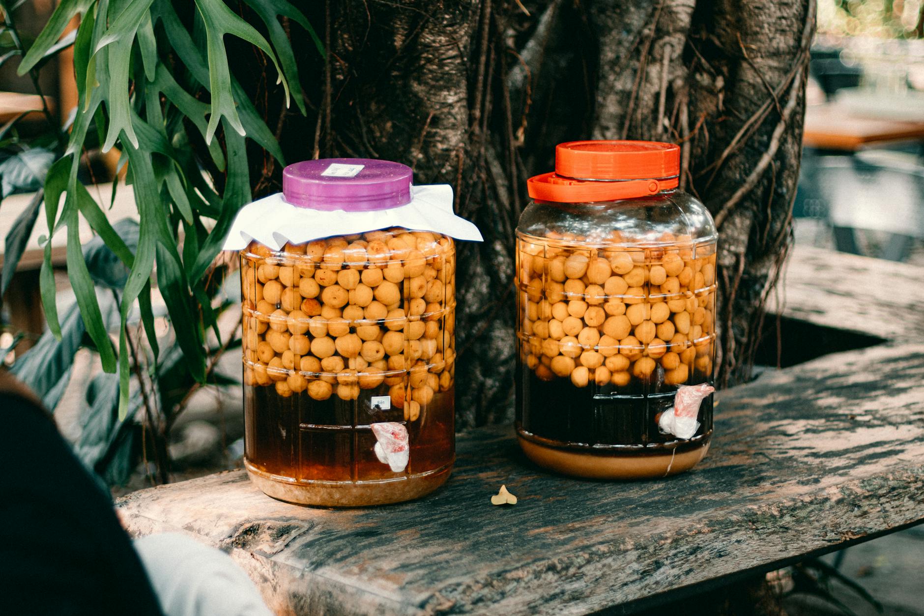 Słoje z owocami w zalewie stojące na rustykalnym drewnianym stole na zewnątrz